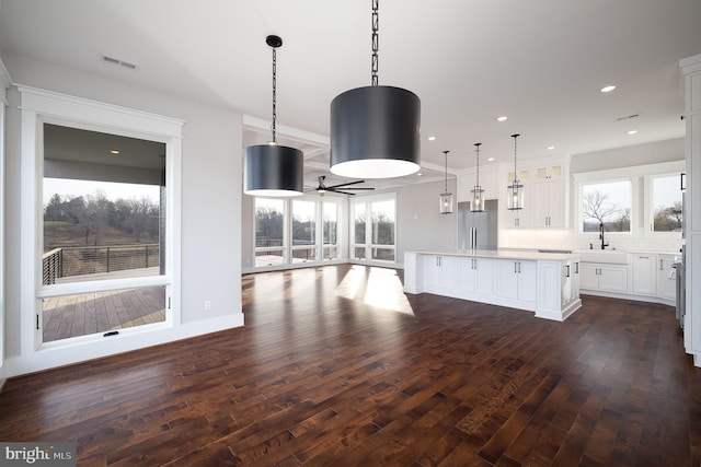 kitchen featuring decorative light fixtures, a kitchen island, dark hardwood / wood-style floors, and a healthy amount of sunlight