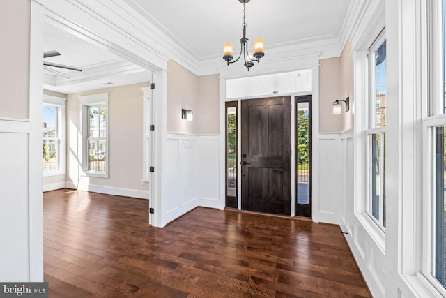 entryway with ornamental molding, dark hardwood / wood-style flooring, and a chandelier