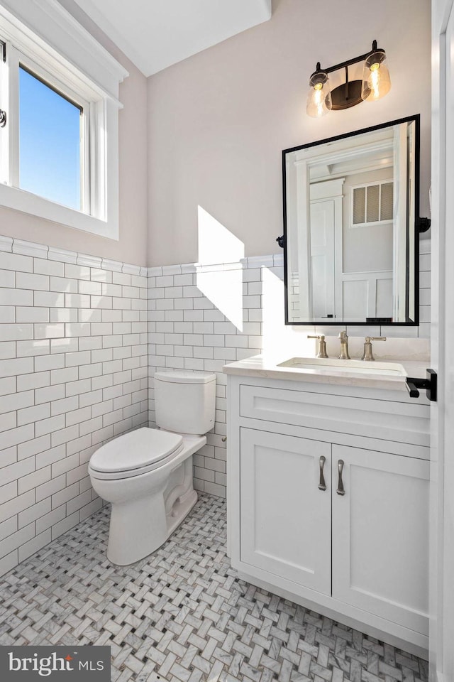 bathroom with vanity, tile walls, and toilet