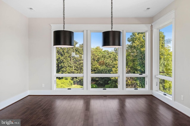 unfurnished dining area featuring a healthy amount of sunlight and dark hardwood / wood-style floors