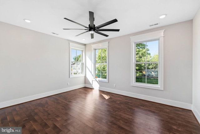 spare room featuring a healthy amount of sunlight, dark hardwood / wood-style floors, and ceiling fan