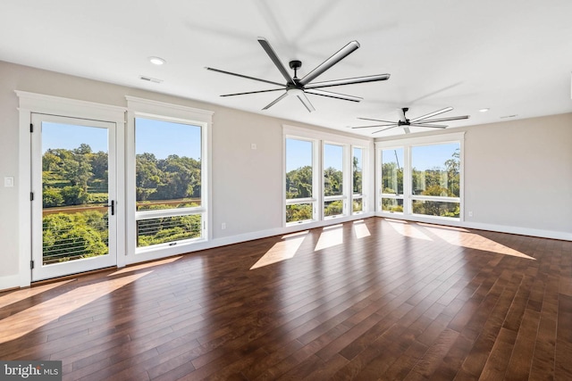 spare room with ceiling fan, plenty of natural light, and dark wood-type flooring