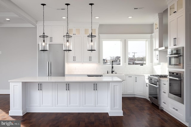 kitchen with white cabinets, sink, appliances with stainless steel finishes, a center island, and dark hardwood / wood-style flooring