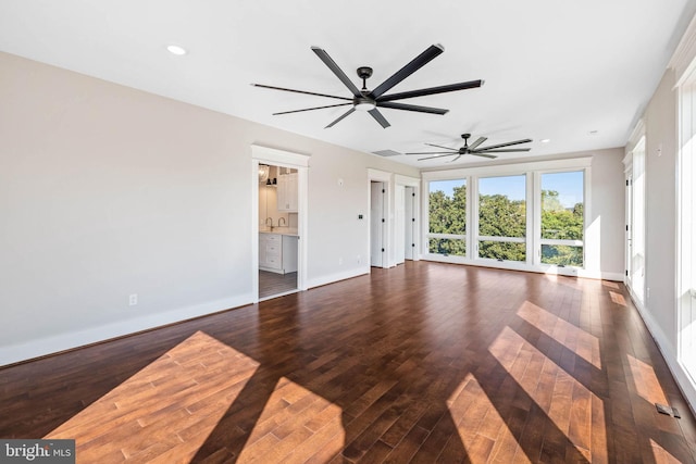 unfurnished living room featuring ceiling fan and dark wood-type flooring