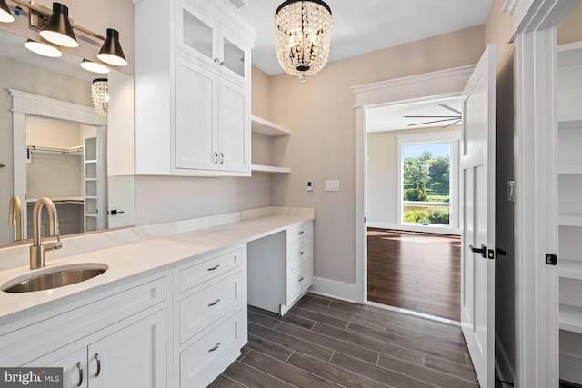 kitchen with white cabinetry, light stone counters, pendant lighting, dark hardwood / wood-style floors, and sink