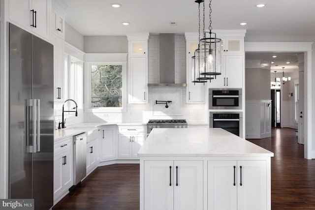 kitchen with white cabinetry, wall chimney range hood, stainless steel appliances, and light stone counters