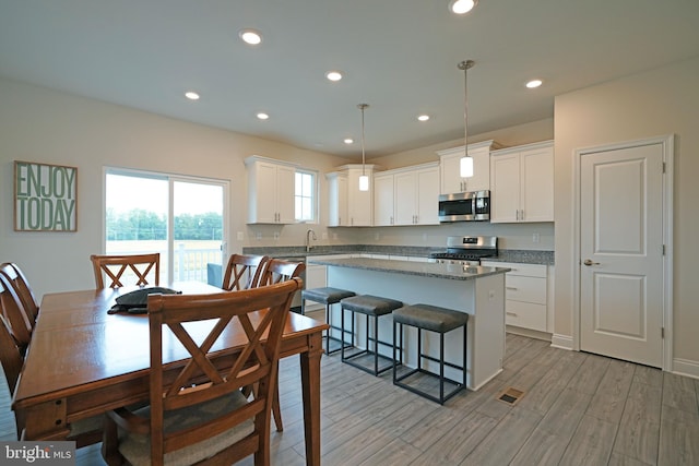 kitchen featuring pendant lighting, stainless steel appliances, white cabinets, and a center island