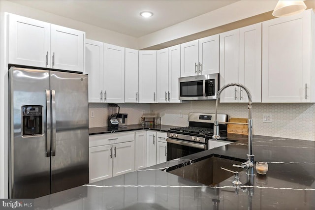 kitchen with backsplash, white cabinetry, appliances with stainless steel finishes, and sink