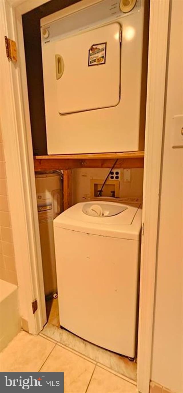 laundry area featuring electric panel, light tile patterned flooring, and stacked washing maching and dryer