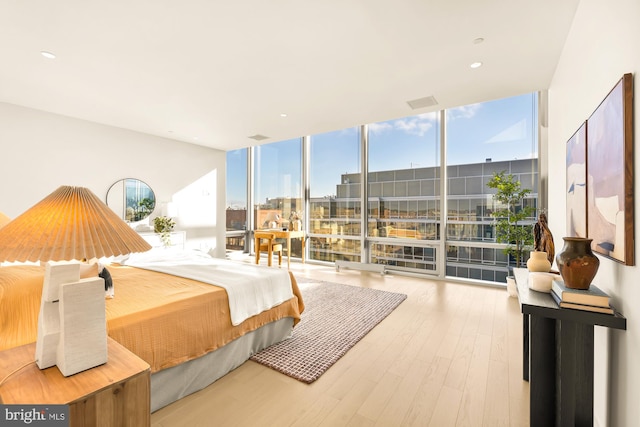 bedroom featuring a wall of windows, light hardwood / wood-style flooring, and multiple windows