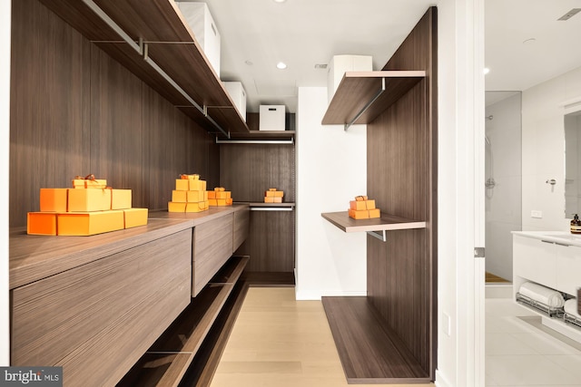 walk in closet with sink and light wood-type flooring