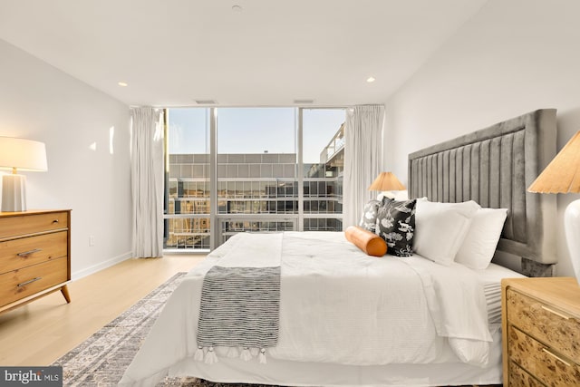 bedroom with a wall of windows and light wood-type flooring