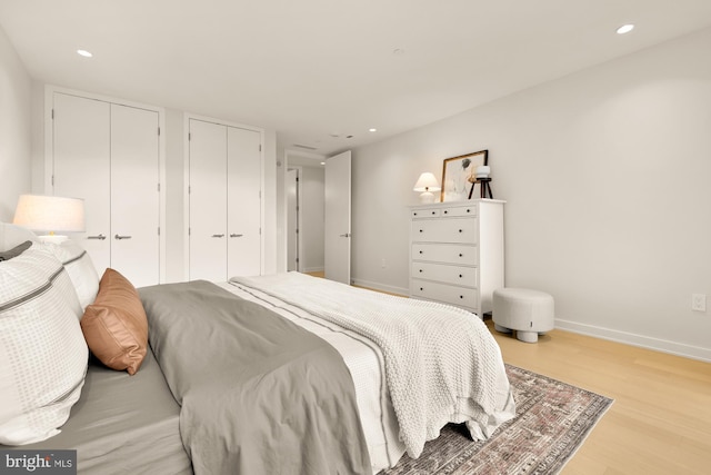 bedroom featuring light wood-type flooring and multiple closets