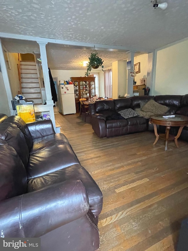 living room with ornate columns, a textured ceiling, and hardwood / wood-style floors