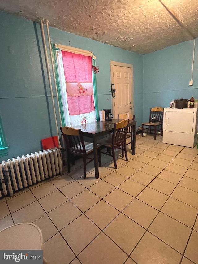 dining room with radiator heating unit, washer / dryer, a textured ceiling, and tile patterned floors