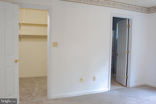 unfurnished bedroom featuring light colored carpet, a walk in closet, and a closet