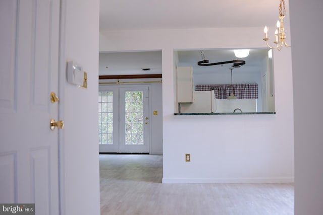 interior space featuring a notable chandelier, light hardwood / wood-style floors, and french doors