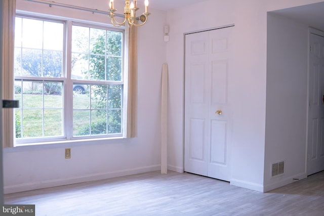 unfurnished bedroom with light hardwood / wood-style flooring, multiple windows, and a notable chandelier