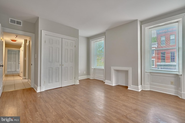 unfurnished bedroom with light wood-type flooring and a closet