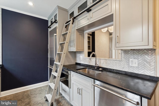 kitchen featuring sink, a barn door, decorative backsplash, crown molding, and stainless steel dishwasher