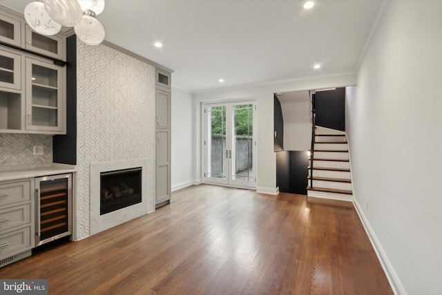 unfurnished living room with ornamental molding, bar area, dark hardwood / wood-style floors, and wine cooler