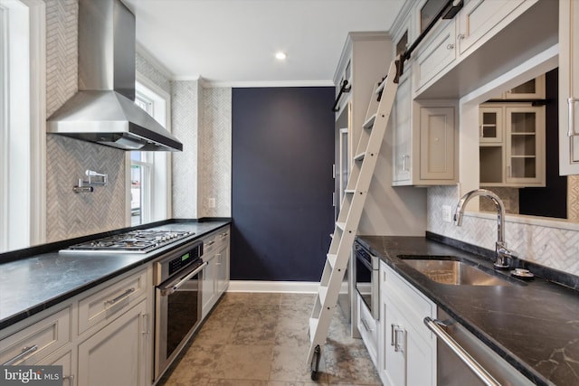 kitchen with sink, wall chimney exhaust hood, stainless steel appliances, decorative backsplash, and ornamental molding