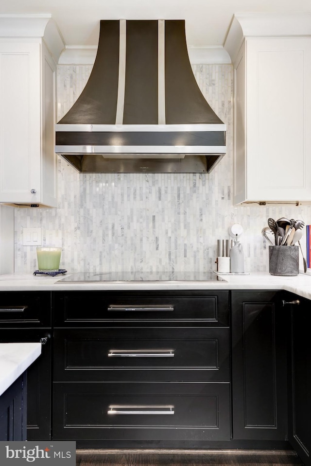 kitchen featuring white cabinets, wall chimney range hood, and black electric cooktop