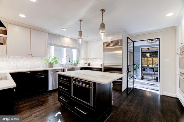 kitchen with dark hardwood / wood-style floors, a kitchen island, white cabinetry, and appliances with stainless steel finishes