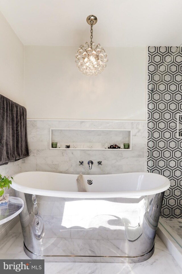 bathroom featuring a washtub, a chandelier, and tile walls