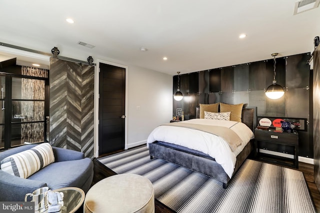 bedroom with hardwood / wood-style floors and a barn door