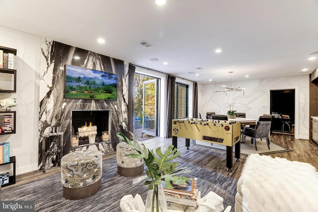 recreation room with hardwood / wood-style flooring, a notable chandelier, and a fireplace