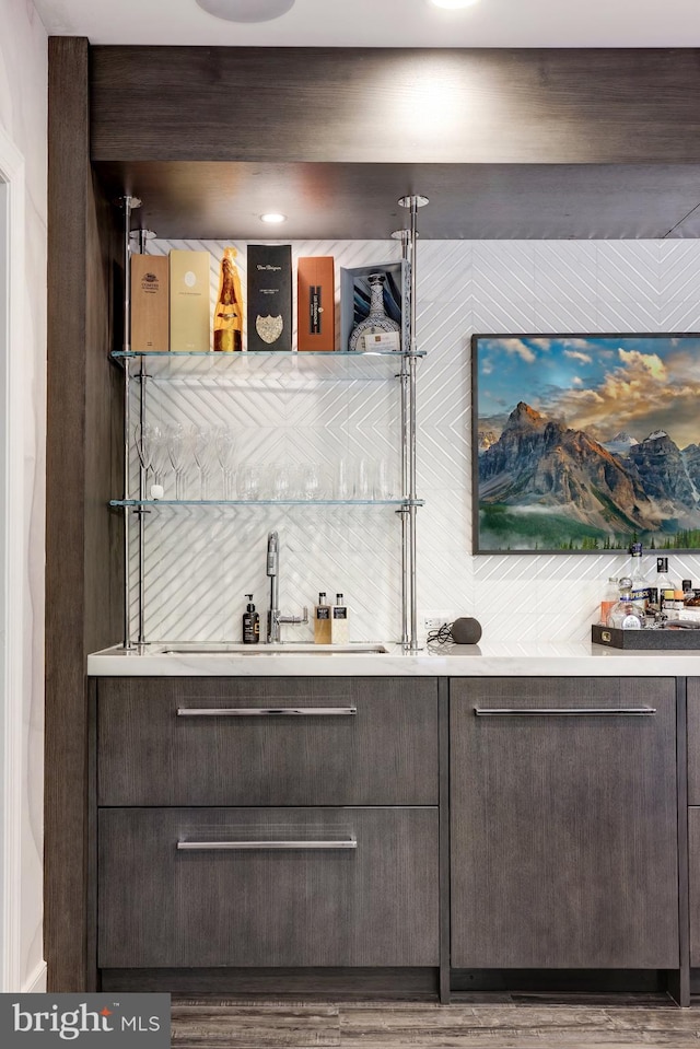 bar with hardwood / wood-style floors, dark brown cabinetry, and sink