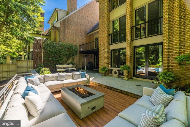 view of patio / terrace featuring a balcony, an outdoor living space with a fire pit, and french doors