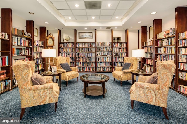 living area with ornamental molding, a tray ceiling, and dark colored carpet