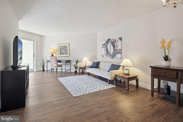 living room with an inviting chandelier, a textured ceiling, and dark wood-type flooring