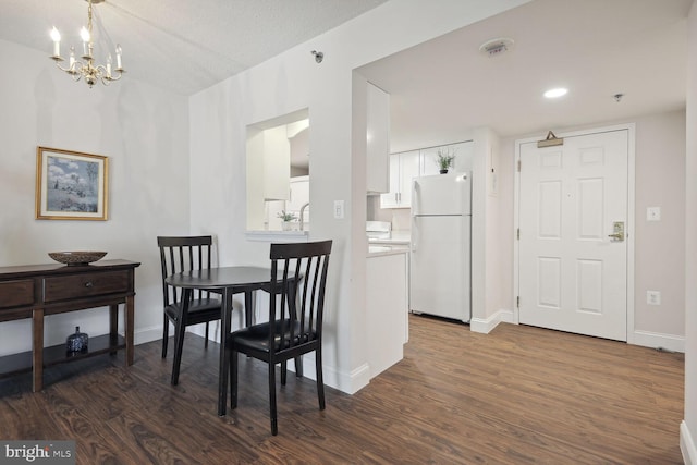 dining space with an inviting chandelier, dark hardwood / wood-style floors, and a textured ceiling