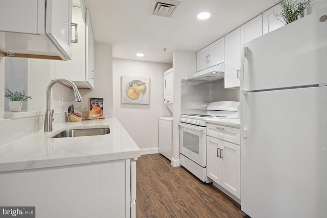 kitchen featuring stacked washer / dryer, dark wood-type flooring, sink, white cabinetry, and white appliances