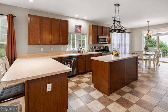 kitchen featuring stainless steel appliances, a chandelier, sink, a kitchen island, and pendant lighting