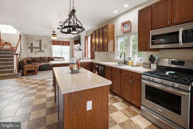 kitchen featuring ceiling fan with notable chandelier, a center island, hanging light fixtures, sink, and appliances with stainless steel finishes