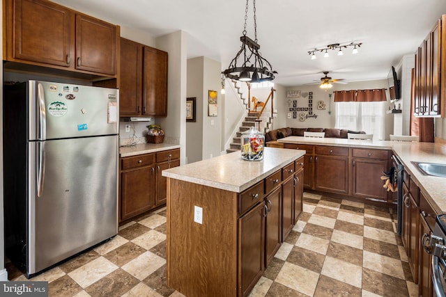 kitchen featuring stainless steel refrigerator, kitchen peninsula, ceiling fan, hanging light fixtures, and a center island