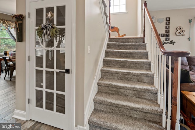 stairs with a wealth of natural light and hardwood / wood-style flooring