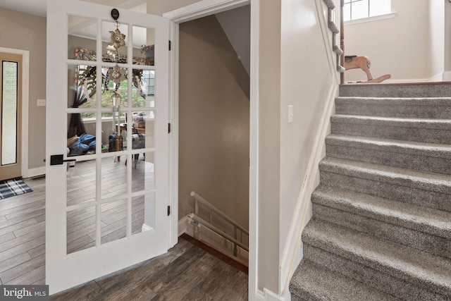 staircase with wood-type flooring and a healthy amount of sunlight