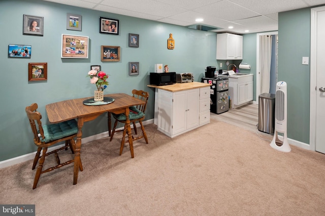 kitchen with a paneled ceiling, sink, light carpet, and white cabinets