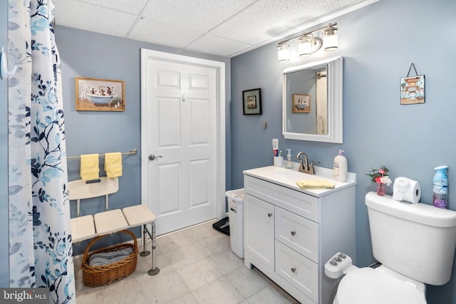 bathroom with a paneled ceiling, toilet, and vanity