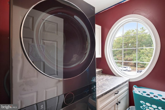 laundry room with cabinets and stacked washing maching and dryer