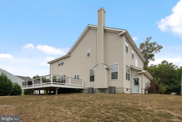 back of property featuring central air condition unit, a wooden deck, and a yard