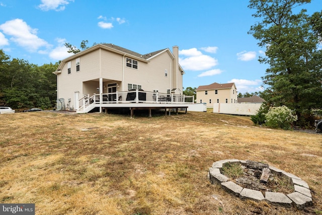 rear view of property with a deck, a lawn, and an outdoor fire pit