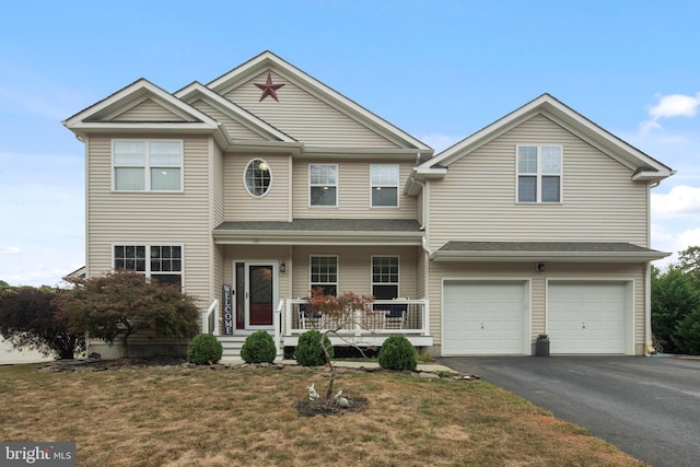 view of front of house with a garage, a front yard, and a porch