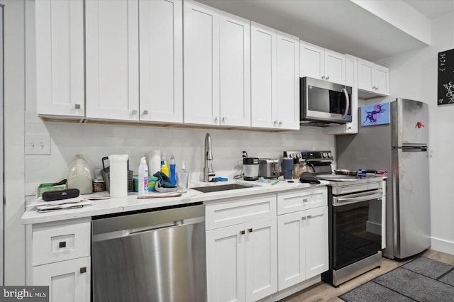 kitchen featuring white cabinets, appliances with stainless steel finishes, light wood-type flooring, and sink