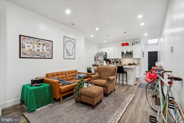 living area with recessed lighting, baseboards, and light wood-type flooring